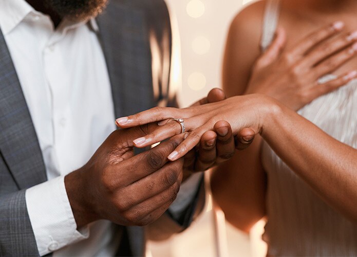Man holding hand of woman wearing engagement ring