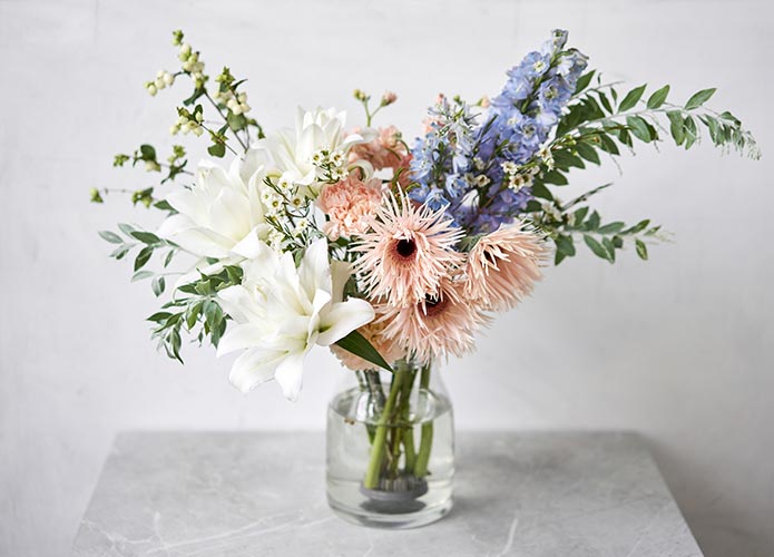 Vase of muted, pink, blue and white flowers